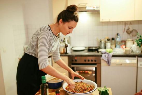 Junge Frau bereitet Essen in der Küche zu 