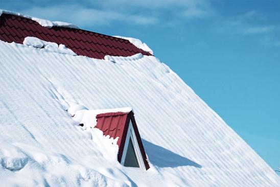 Schneebedecktes Steildach mit kleiner Gaube