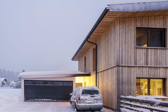 Holzhaus mit Garage und abgeflachtem Dach im Schnee