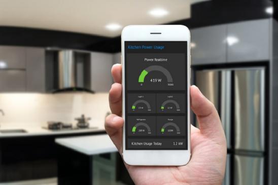 Internet of things , iot , smart home , kitchen and network connect concept. Human hand holding white phone and smart home application to count power usage energy with blur kitchen background