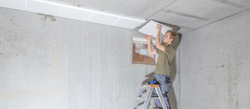 Handwerker dämmt eine Kellerdecke.