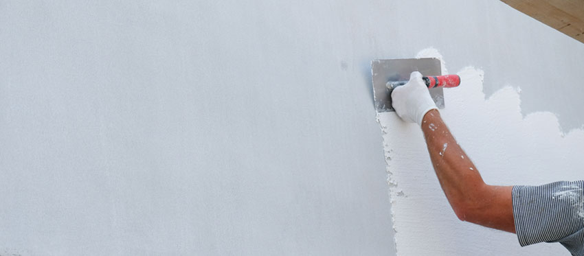 Arbeiter spachtelt eine Wand aus 