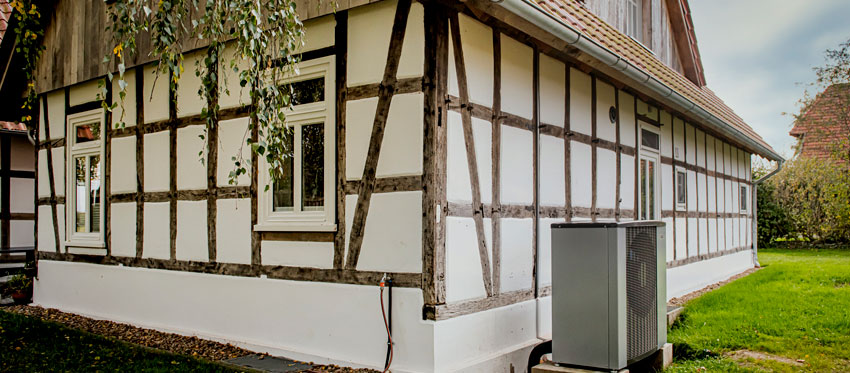 Älteres Fachwerkhaus mit Wärmepumpe vor Hauswand
