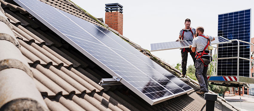 Zwei Facharbeiter montieren Solarmodule aufs Dach