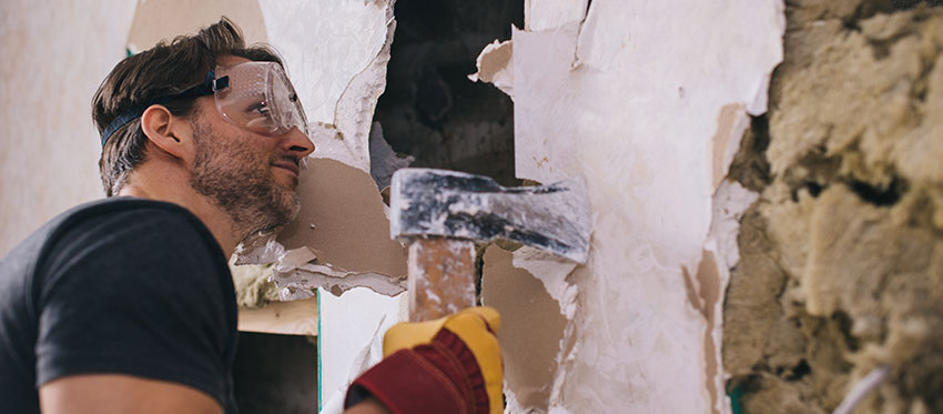 Mann mit Axt beim Durchbrechen einer Zimmerwand