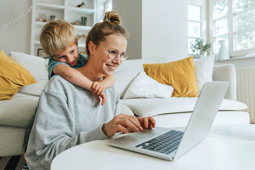 Frau mit Kind im Wohnzimmer am Laptop